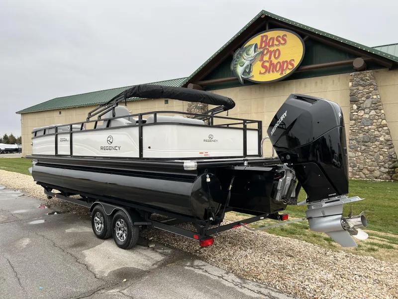 Slide: The Image of 2024 Regency 250 DL3 pontoon boat on trailer outside Bass Pro Shops. - 7