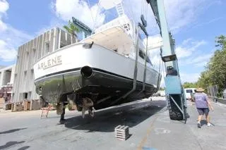 Slide: The Image of Precision Convertible 2001 boat named Arlene being lifted by a crane at a shipyard. - 25