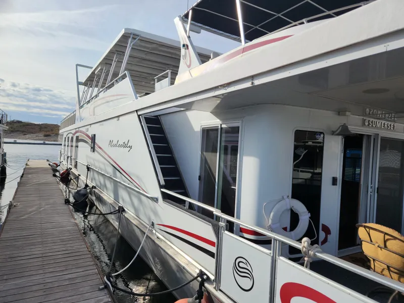 Slide: The Image of 2008 Sumerset Houseboat 20' x 100' docked, side view with visible deck and railings. - 2