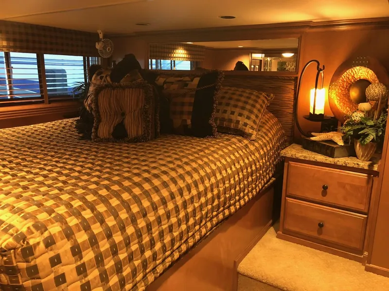 Slide: The Image of Cozy bedroom interior of a 2008 Sumerset Houseboat with checkered bedding and warm lighting. - 20