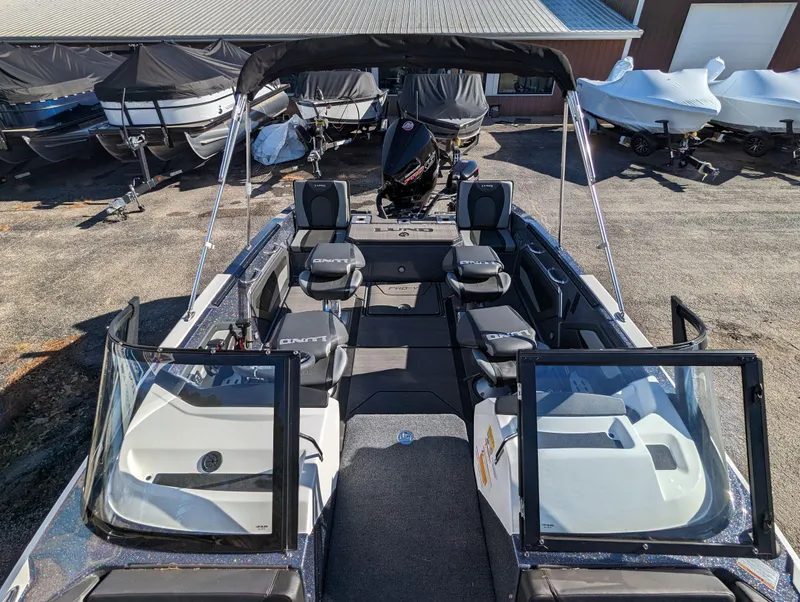 Slide: The Image of 2025 Lund 202 Pro-V GL boat with open cockpit and seating, parked outdoors. - 5