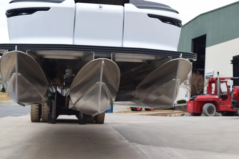 Slide: The Image of 2024 Manitou 22' Cruise Switchback Stealth pontoon boat rear view, showcasing triple pontoons. - 17