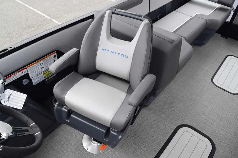 Slide: The Image of 2024 Manitou 22' Cruise Switchback Stealth boat interior with gray captain's chair and seating. - 33