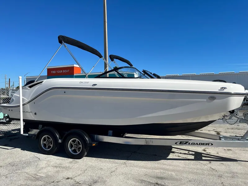Slide: The Image of 2021 Bayliner DX 2200 boat on a trailer with a Mercury outboard motor. - 2
