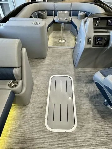 Slide: The Image of 2024 Bennington 25 LTSB boat interior with gray seating, blue LED lighting, and cup holders. - 21