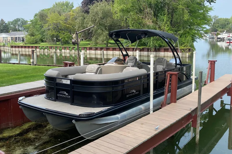 Slide: The Image of 2018 Bennington G25 pontoon boat docked by a lush, green riverside. - 20