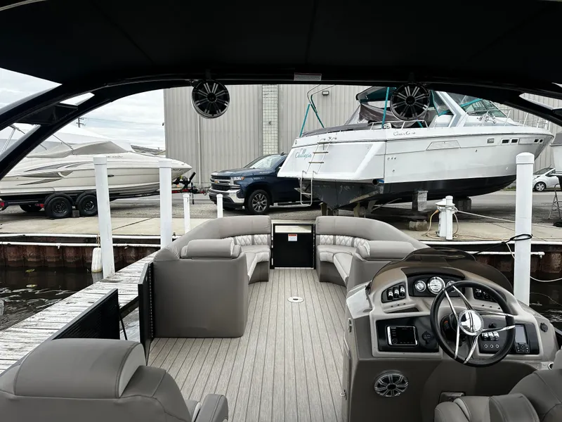 Slide: The Image of 2018 Bennington G25 pontoon boat interior at dock with luxury seating and steering console. - 3
