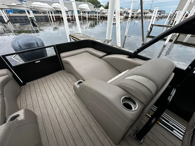 Slide: The Image of 2018 Bennington G25 pontoon boat interior with beige seating and cup holders, docked at marina. - 9