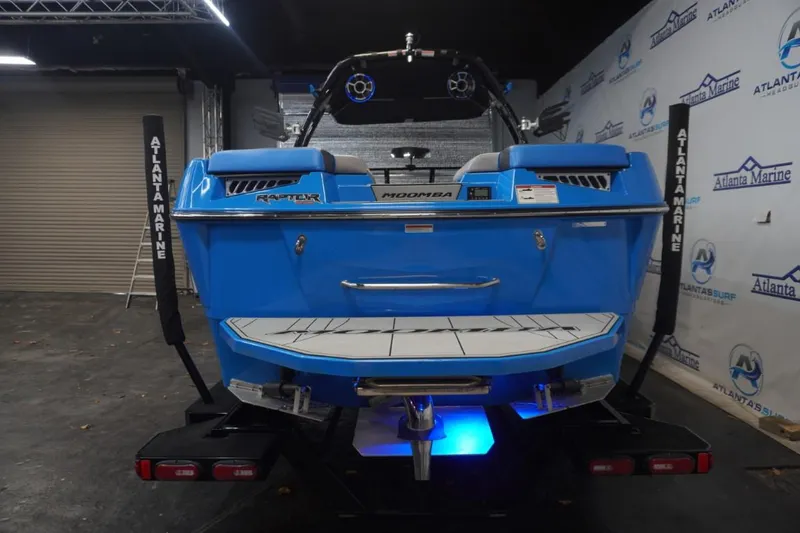 Slide: The Image of Rear view of a blue 2021 Moomba Makai boat in a showroom. - 4