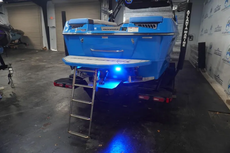 Slide: The Image of Rear view of a blue 2021 Moomba Makai boat with illuminated swim platform. - 8