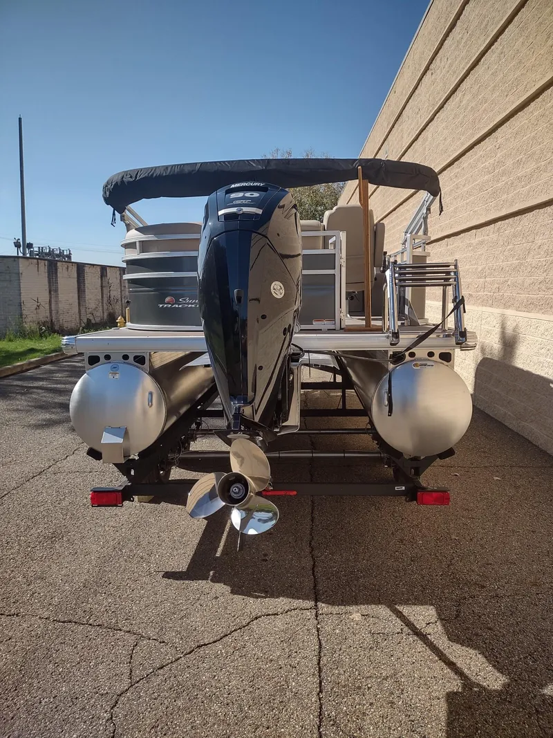 Slide: The Image of 2024 Sun Tracker Party Barge 20 DLX pontoon boat, rear view with motor, parked outdoors. - 12