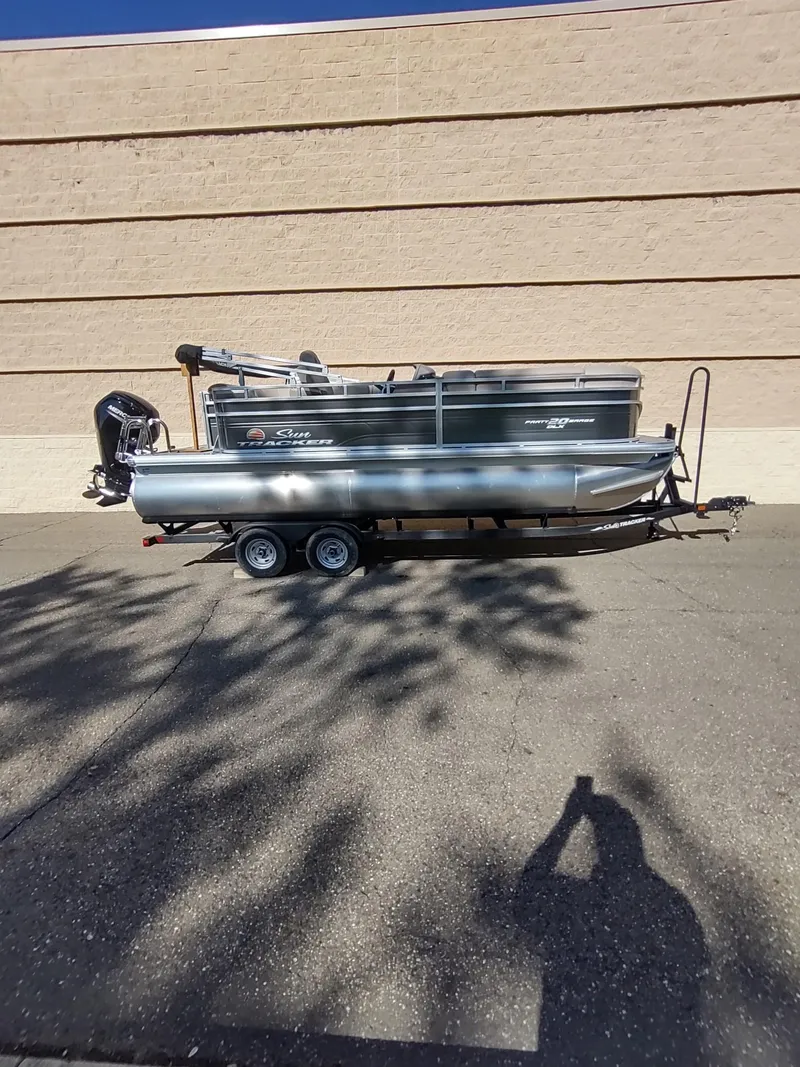 Slide: The Image of 2024 Sun Tracker Party Barge 20 DLX pontoon boat on trailer, parked outdoors. - 4