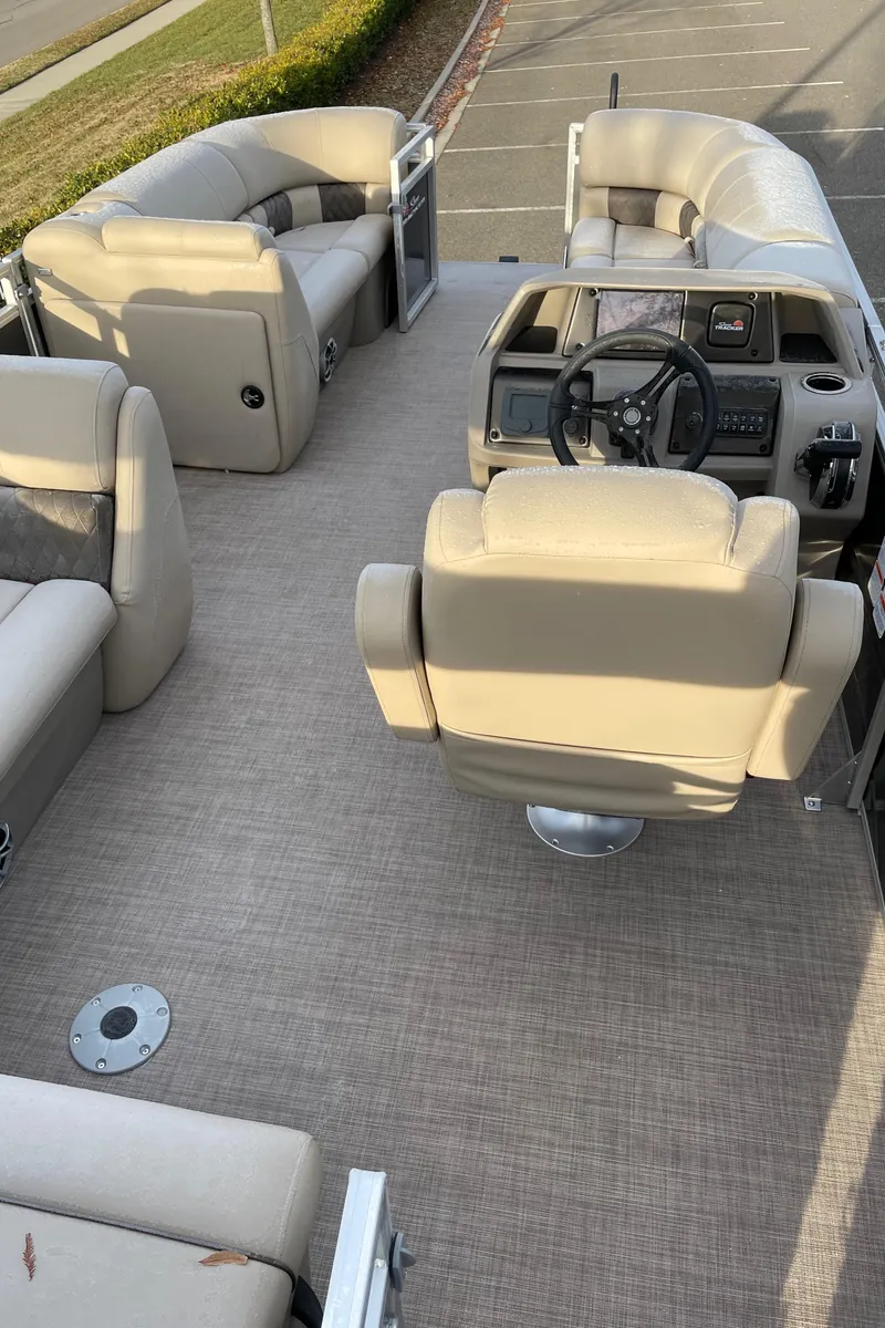 Slide: The Image of 2024 Sun Tracker Party Barge 20 DLX interior with beige seating and steering console. - 3