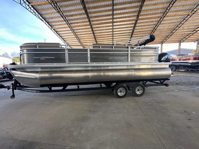 Slide: The Image of 2024 Sun Tracker Party Barge 22 RF XP3 pontoon boat under a covered dock. - 2