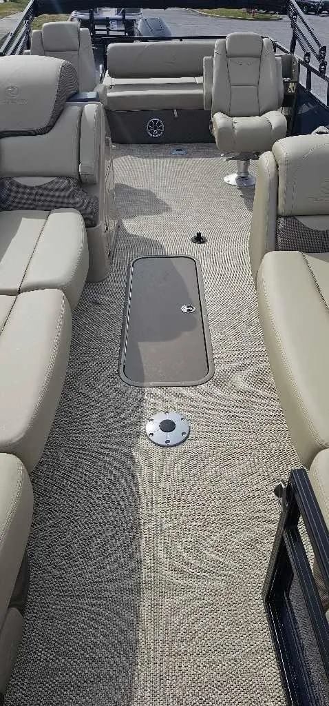 Slide: The Image of 2024 Regency 250 DL3 pontoon boat interior with beige seating and carpet flooring. - 3