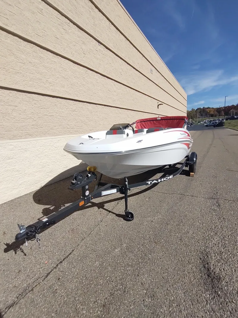 Slide: The Image of 2024 Tahoe T16 boat on trailer, white with red interior, parked outdoors. - 2