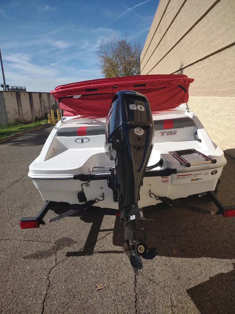 Slide: The Image of 2024 Tahoe T16 boat with 60 HP outboard motor, parked outdoors. - 4