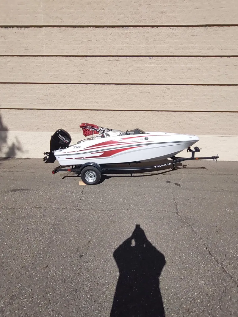 Slide: The Image of 2024 Tahoe T16 boat with red accents on a trailer, parked outdoors. - 5