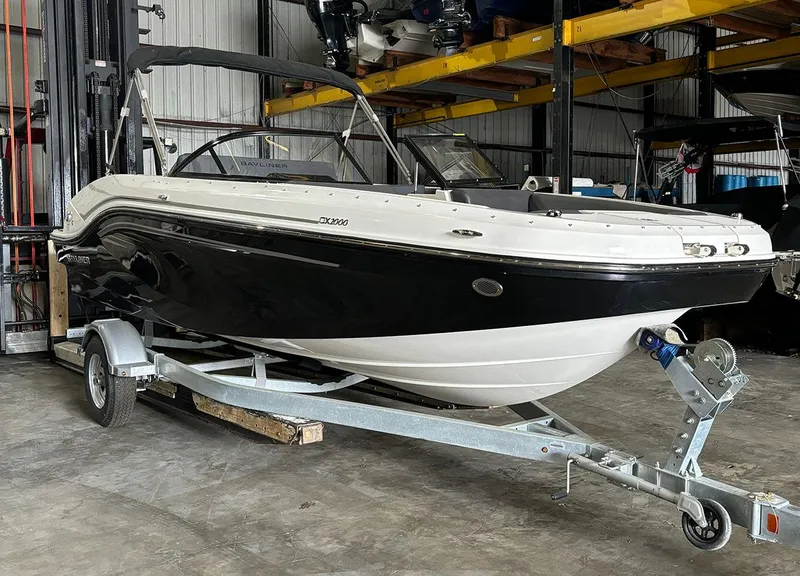 The Image of 2024 Bayliner DX 2000 boat on a trailer in a storage facility. - 0