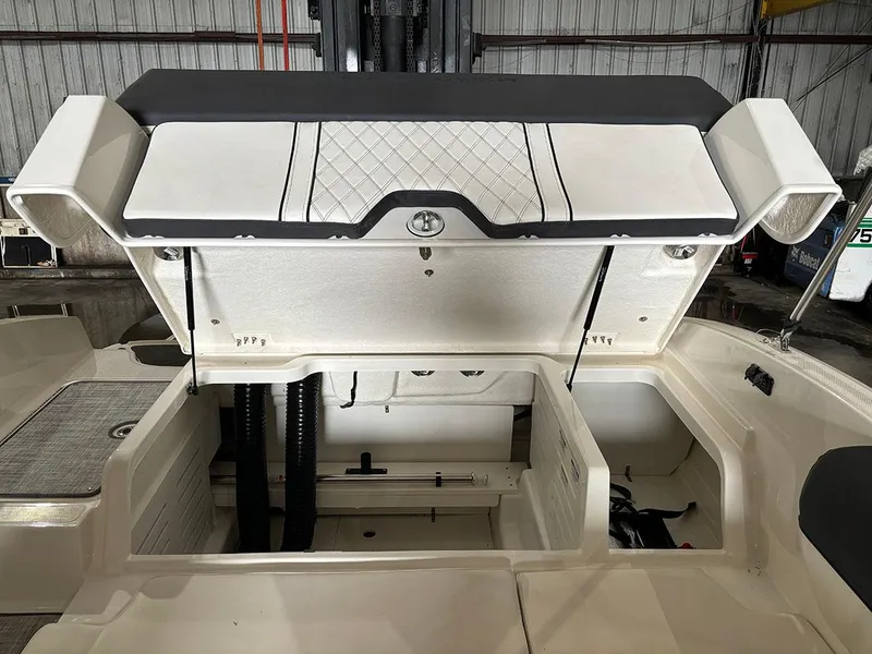 Slide: The Image of 2024 Bayliner DX 2000 boat storage compartment with open hatch in a warehouse. - 7