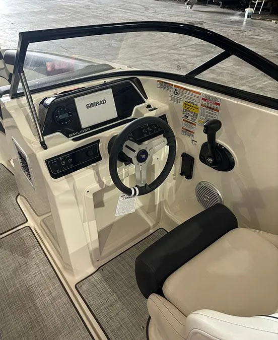 Slide: The Image of 2024 Bayliner DX 2000 boat cockpit with steering wheel and Simrad navigation system. - 9