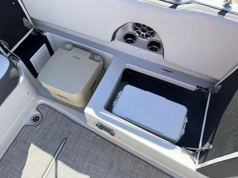 Slide: The Image of 2023 Crownline E205XS boat interior with storage compartments and portable toilet. - 24