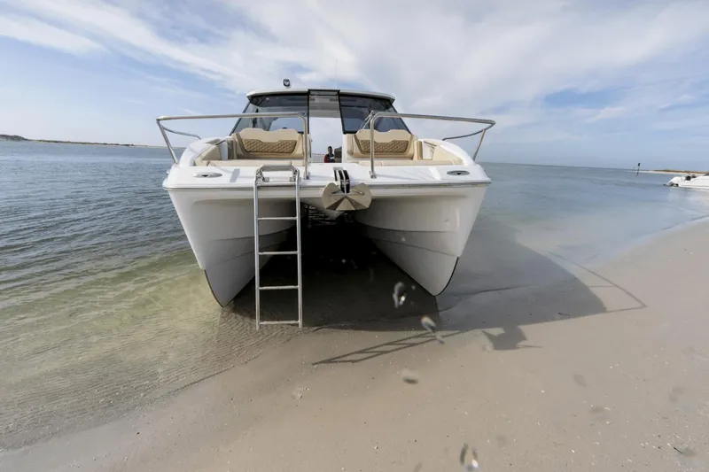Slide: The Image of 2024 Aquila 36 Sport catamaran beached on sandy shore with clear blue sky. - 4