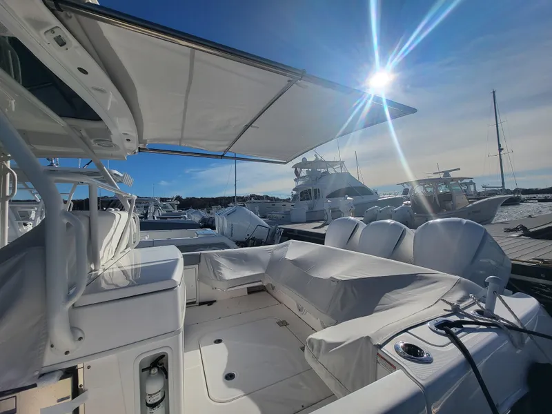 Slide: The Image of 2018 Everglades 360 LXC boat with covered seating area docked at marina. - 11