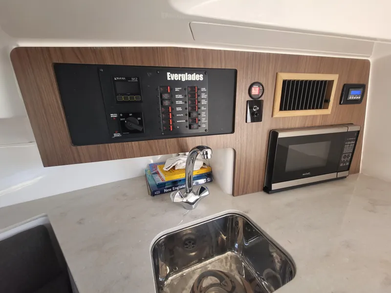 Slide: The Image of Control panel and kitchenette in 2018 Everglades 360 LXC boat, featuring sink and microwave. - 25