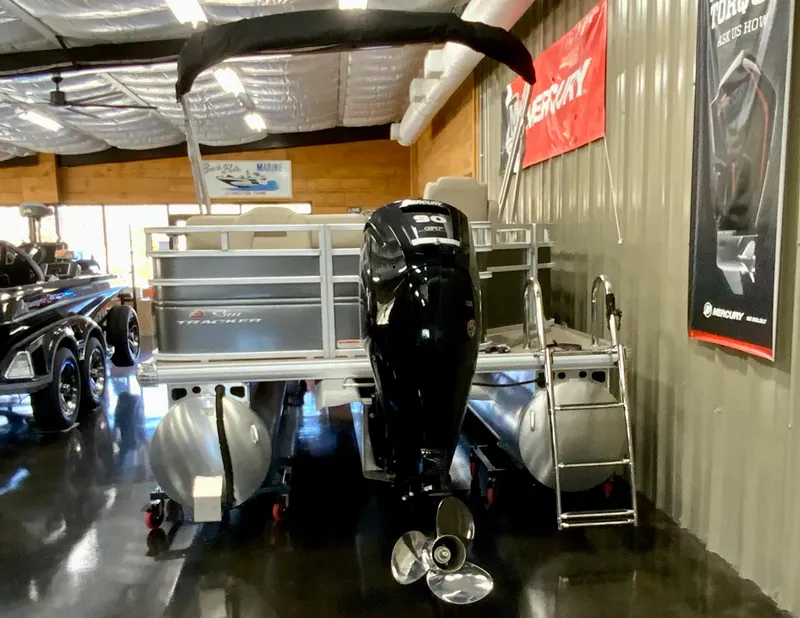 Slide: The Image of 2024 Sun Tracker Fishin' Barge 20 DLX pontoon boat in showroom with outboard motor. - 4