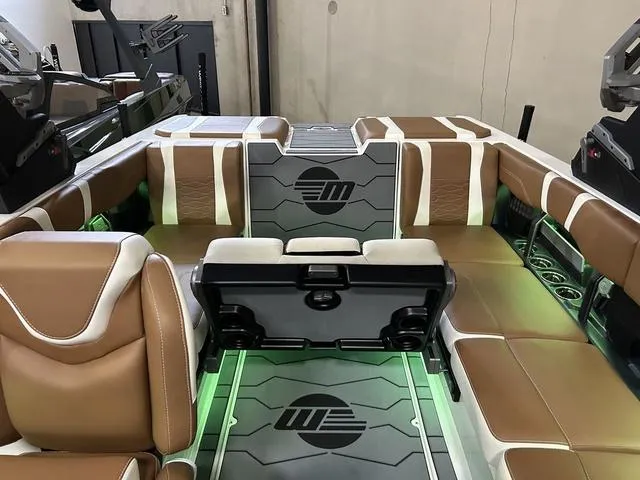 Slide: The Image of 2024 Malibu 23 MXZ boat interior with brown and white seating, green LED lighting. - 16