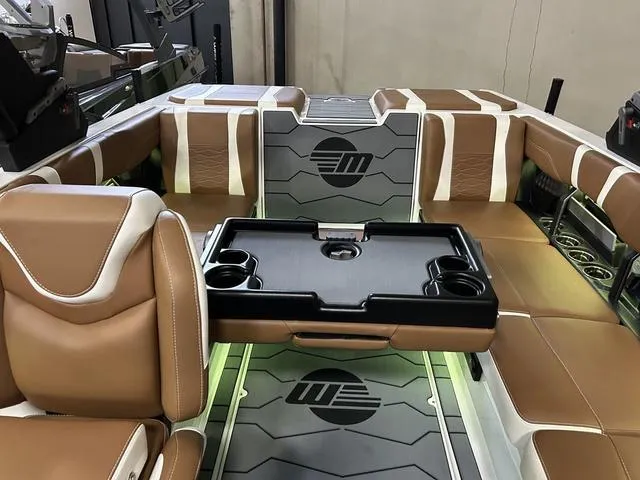 Slide: The Image of 2024 Malibu 23 MXZ boat interior with brown and white seating and a central table. - 17