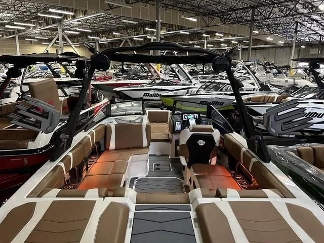 Slide: The Image of 2024 Malibu 23 MXZ boat interior in showroom with multiple boats. - 6