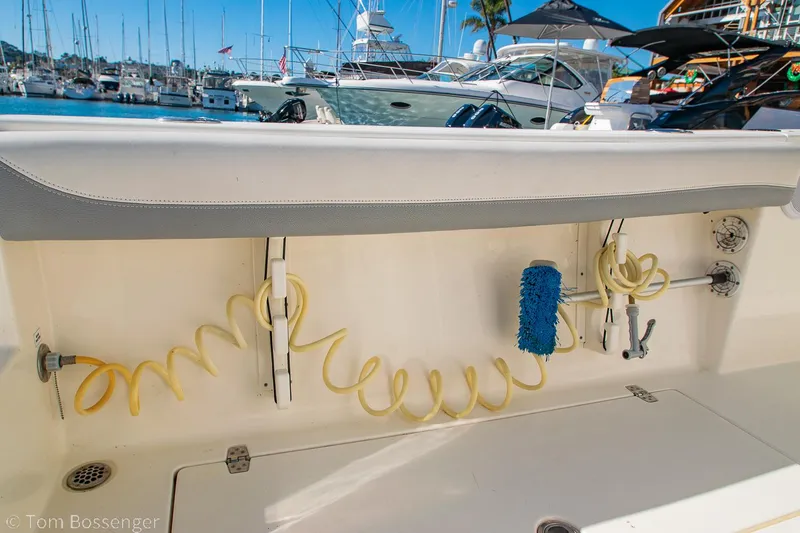Slide: The Image of 2018 Cobia 240 CC boat deck with cleaning tools and marina background. - 23