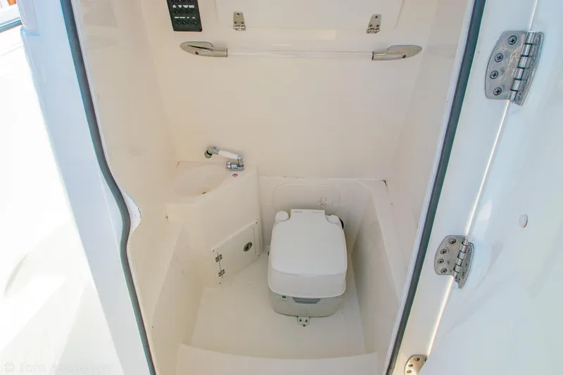 Slide: The Image of 2018 Cobia 240 CC boat interior with compact marine toilet and sink. - 26