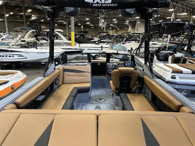 Slide: The Image of 2024 Axis Wake Research A225 boat interior with tan and black seating, displayed in a showroom. - 3