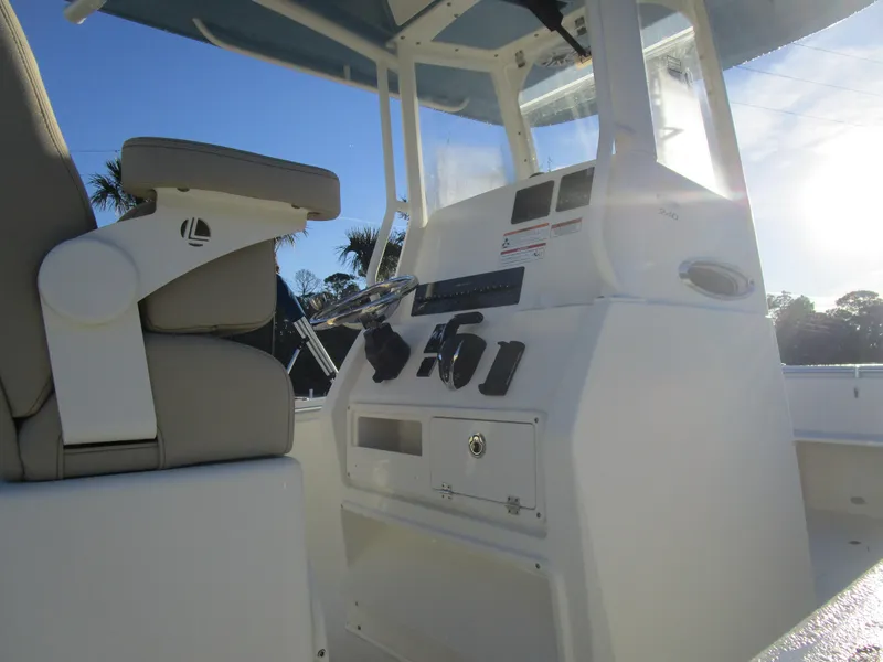 Slide: The Image of 2024 Cobia 240 CC boat console and seating under clear sky. - 6