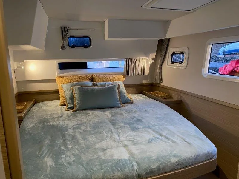 Slide: The Image of Luxurious bedroom interior of 2024 Lagoon 42 catamaran with cozy bedding and ample natural light. - 14