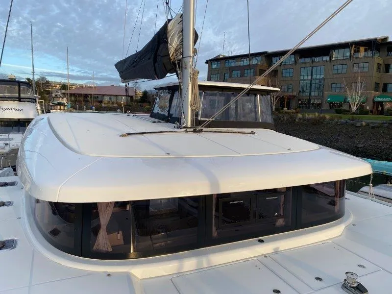 Slide: The Image of 2024 Lagoon 42 catamaran docked at a marina with modern buildings in the background. - 23