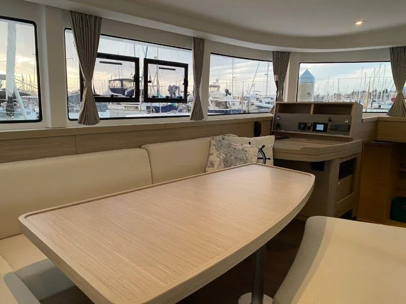Slide: The Image of Interior of 2024 Lagoon 42 catamaran with dining table and marina view. - 2