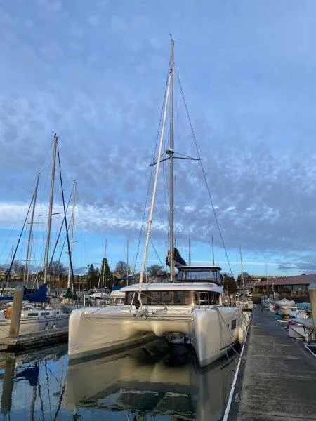Slide: The Image of 2024 Lagoon 42 catamaran docked at a marina under a cloudy sky. - 21