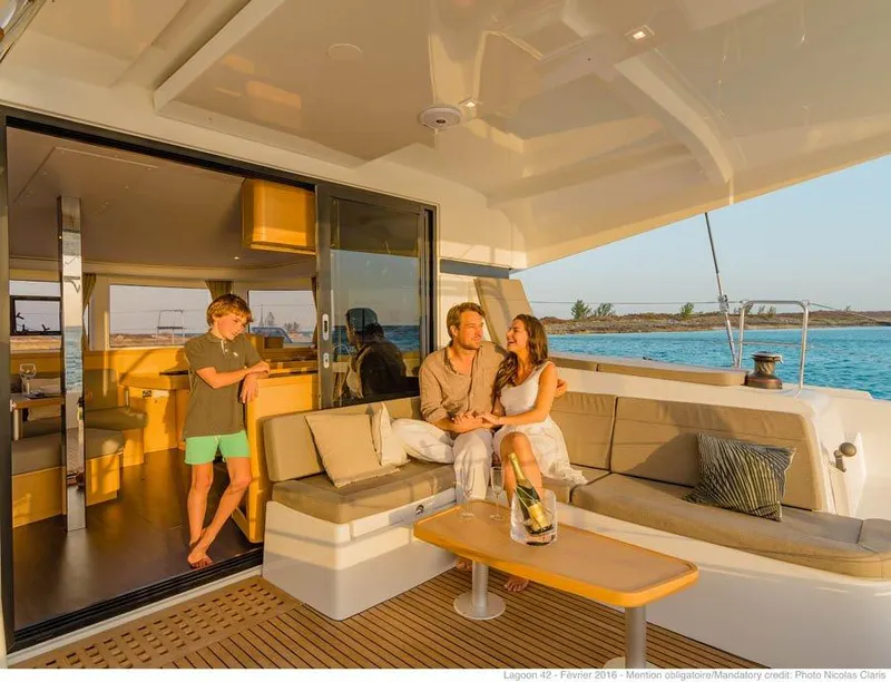 Slide: The Image of 2024 Lagoon 42 catamaran with people relaxing on deck at sunset. - 35