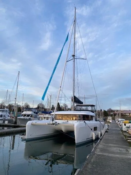 Slide: The Image of 2024 Lagoon 42 catamaran docked at a marina under a blue sky. - 46