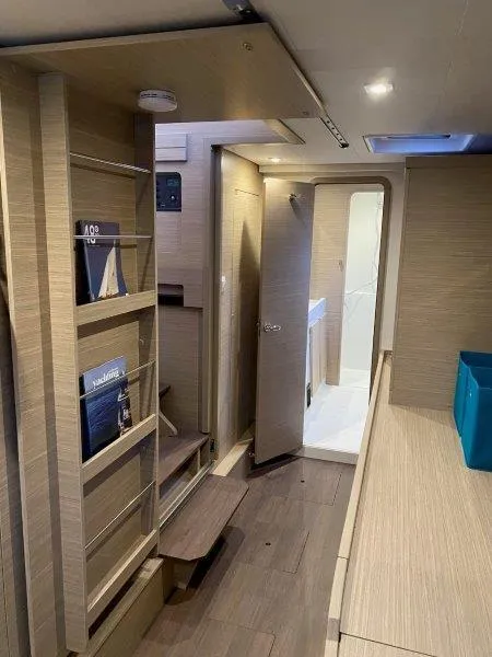 Slide: The Image of Interior of 2024 Lagoon 42 catamaran with modern wooden finish and built-in shelving. - 9