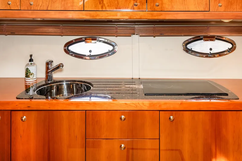Slide: The Image of 2007 Sunseeker Portofino 47 yacht kitchen with wooden cabinets and stainless steel sink. - 33