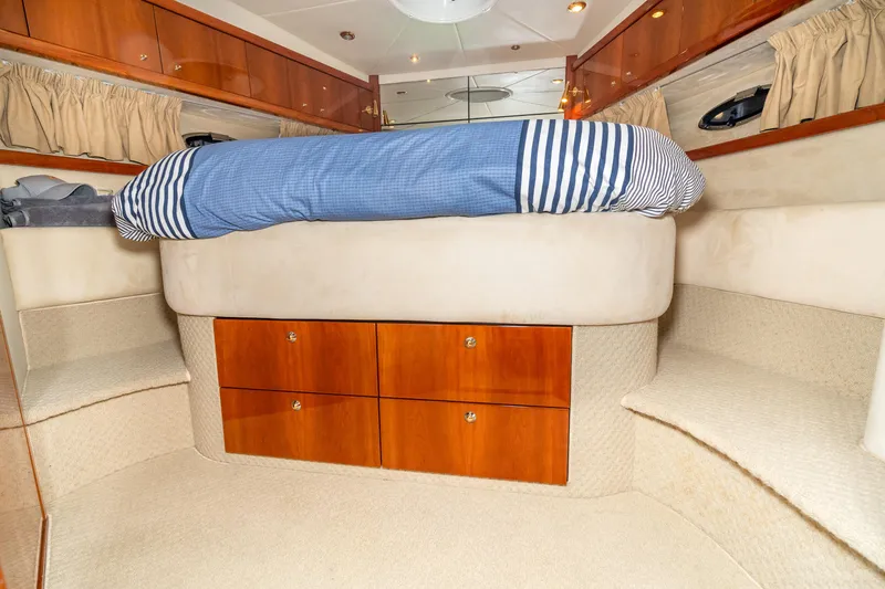 Slide: The Image of 2007 Sunseeker Portofino 47 yacht bedroom with blue-striped bedding and wooden storage drawers. - 42