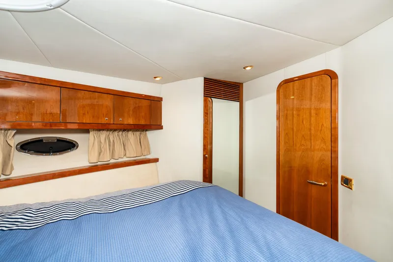 Slide: The Image of 2007 Sunseeker Portofino 47 yacht bedroom with wooden cabinets and blue bedding. - 46