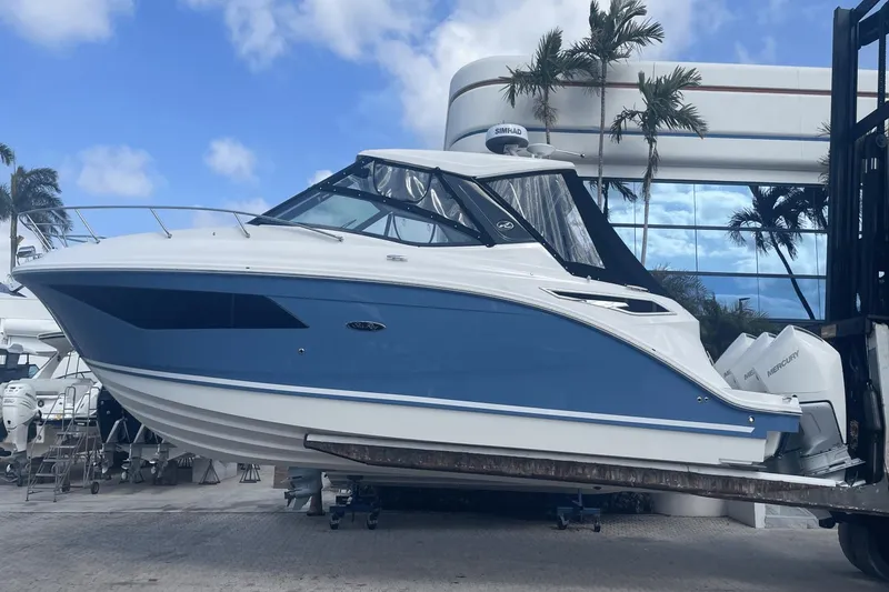 Slide: The Image of 2024 Sea Ray Sundancer 320 Outboard boat displayed outdoors with palm trees and blue sky. - 1