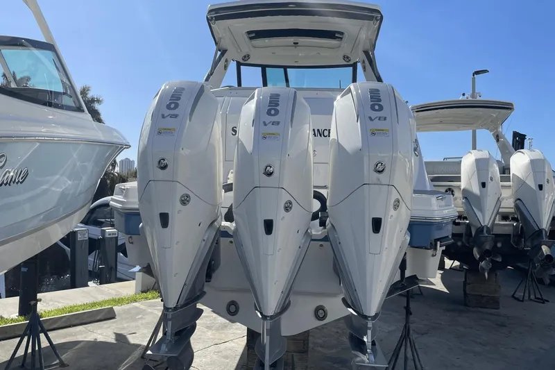 Slide: The Image of 2024 Sea Ray Sundancer 320 Outboard with triple V8 engines, docked under clear blue sky. - 2