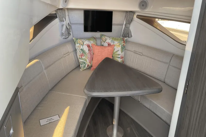 Slide: The Image of 2024 Sea Ray Sundancer 320 Outboard cabin interior with seating, table, and decorative pillows. - 28